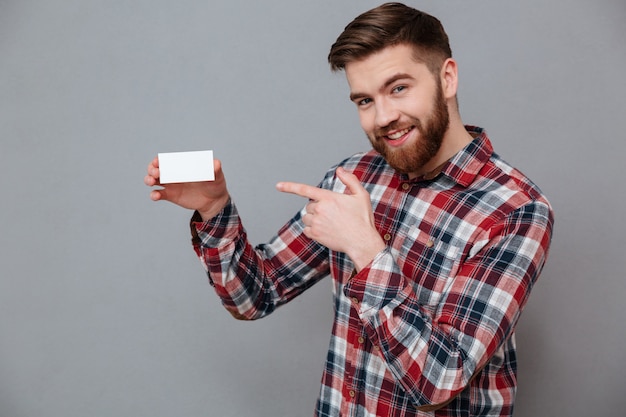 Sorrindo jovem barbudo segurando o cartão de visita em branco