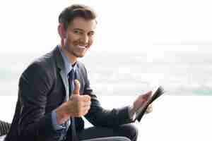 Foto grátis sorrindo jovem empresário com o polegar acima e tablet
