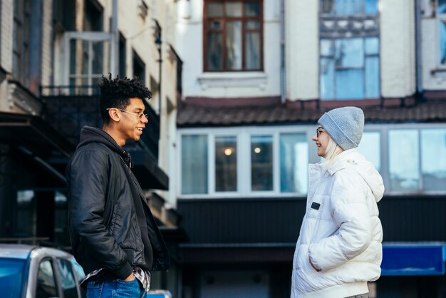 Sorrindo, jovem, interracial, par, com, mãos, em, seu, bolso, olhando um ao outro