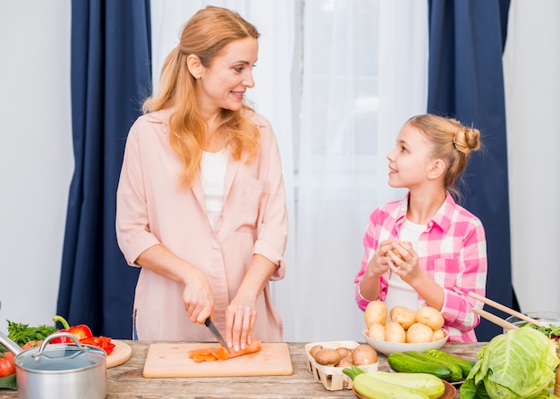 Foto grátis sorrindo, jovem, mãe, e, dela, filha, preparar, a, vegetal, ligado, tábua cortante