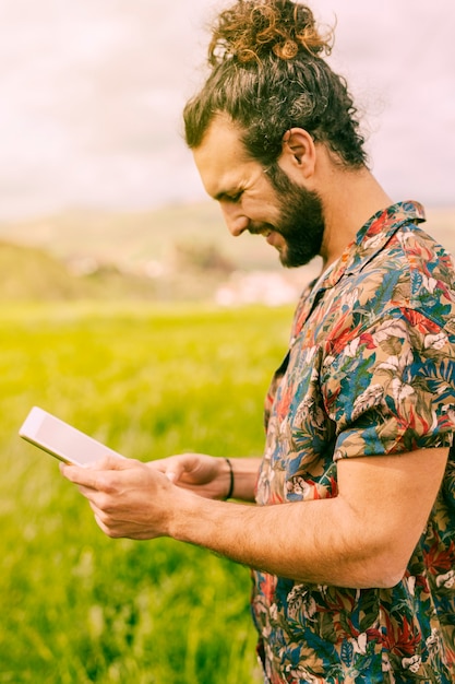 Sorrindo jovem morena em pé com tablet no campo