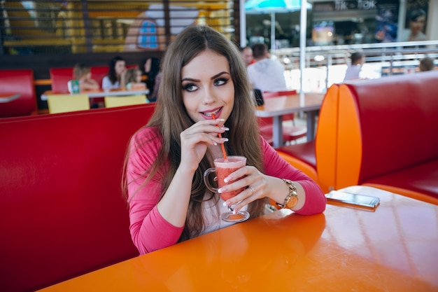 Sorrindo jovem mulher beber um refrigerante