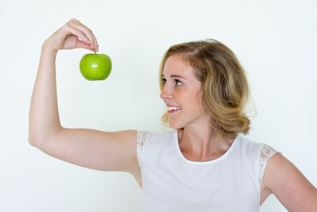 Sorrindo jovem mulher bonita segurando a maçã verde com os dedos