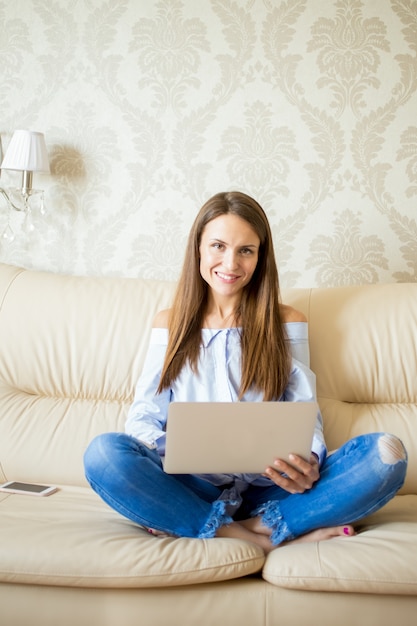 Sorrindo, jovem, mulher, sentando, sofá, touchpad