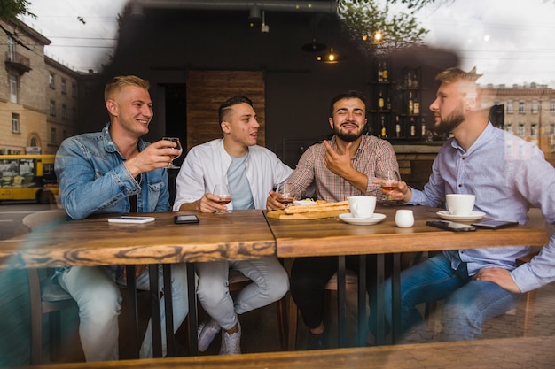 Sorrindo jovens amigos do sexo masculino apreciando as bebidas no restaurante