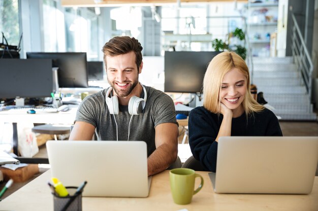 Sorrindo jovens colegas sentados no escritório de coworking