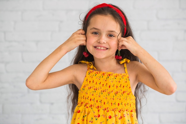 Sorrindo linda garota segurando cerejas perto da orelha como brincos