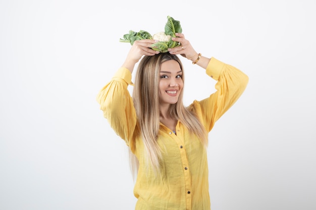 Foto grátis sorrindo linda mulher modelo em pé e segurando a couve-flor.