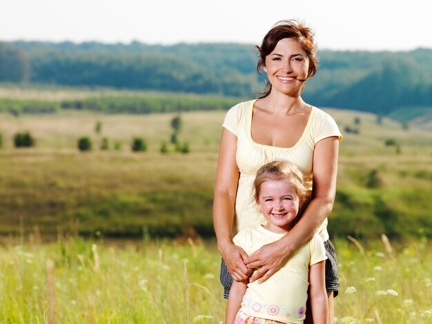 Sorrindo, mãe e filha na natureza.