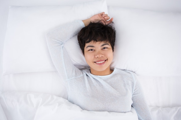 Sorrindo, menina bastante asiática, deitada na cama