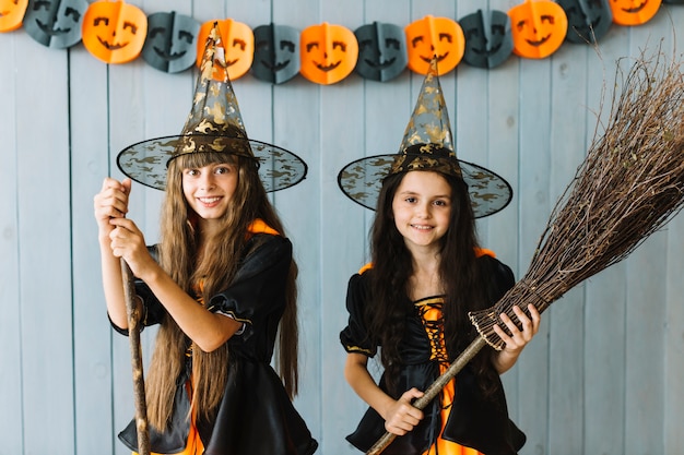 Foto grátis sorrindo, meninas, em, bruxa, ternos, segurando, broomstick, e, vara