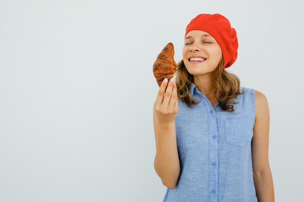 Foto grátis sorrindo mulher bonita cheirando croissant delicioso