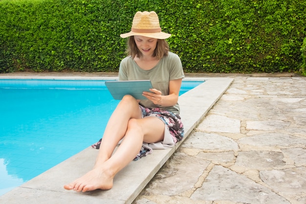 Sorrindo mulher focada trabalhando com tablet na piscina