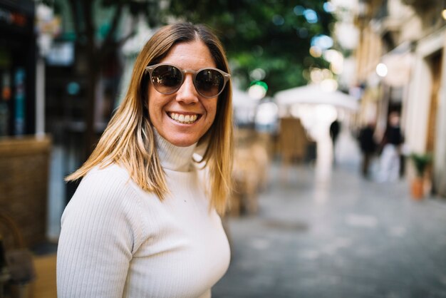 Sorrindo, mulher jovem, com, óculos de sol, rua, em, cidade