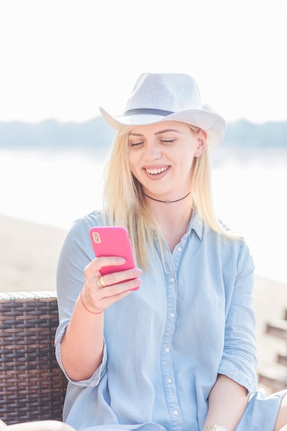 Foto grátis sorrindo, mulher jovem, desgastar, chapéu, segurando, telefone móvel