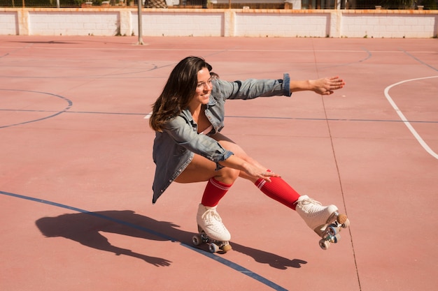 Foto grátis sorrindo, mulher jovem, desgastar, patinador feminino, equilibrar