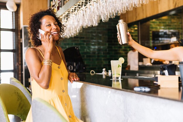 Sorrindo, mulher jovem, falando telefone móvel, em, barra, contador