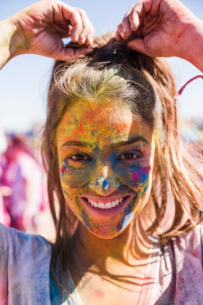 Sorrindo, mulher jovem, rosto, coberto, com, holi, cor, olhando câmera