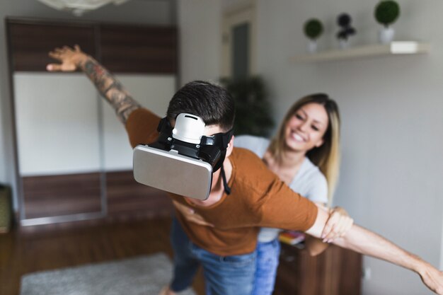 Sorrindo, mulher jovem, segurando, mão homem, desgastar, realidade virtual, headset