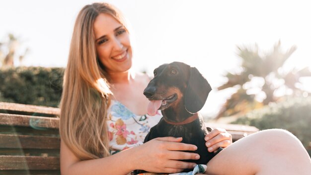 Sorrindo, mulher jovem, sentar-se banco, com, dela, cão, furar lingüeta