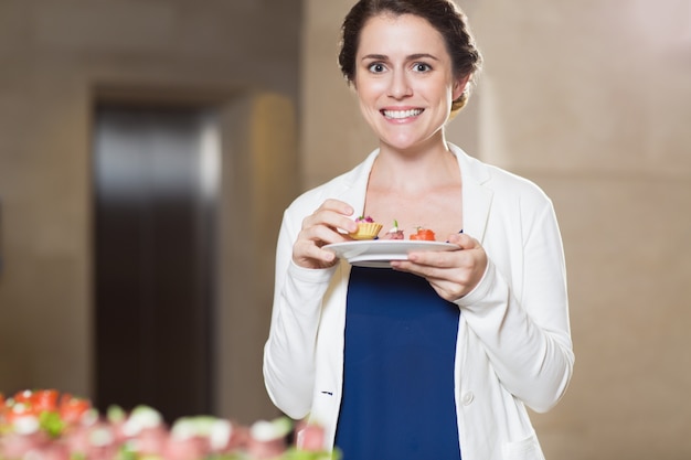 Foto grátis sorrindo mulher que prova snacks na mesa buffet