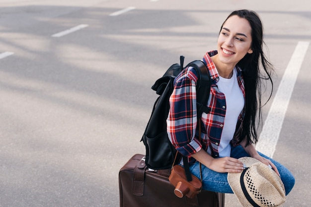 Sorrindo, mulher senta-se, bagagem, saco, com, câmera, e, mochila, em, ao ar livre