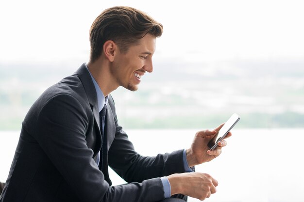 Sorrindo O homem de negócios de meia idade que usa o smartphone