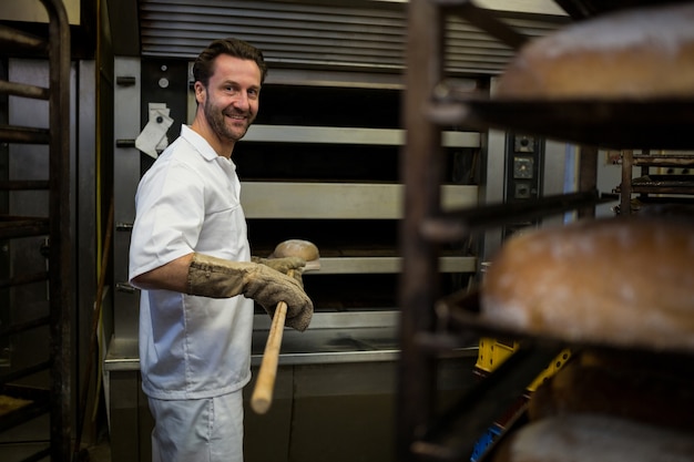 Foto grátis sorrindo padeiro remoção pão cozido do forno