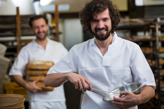 Sorrindo padeiro, segurando uma taça e um batedor