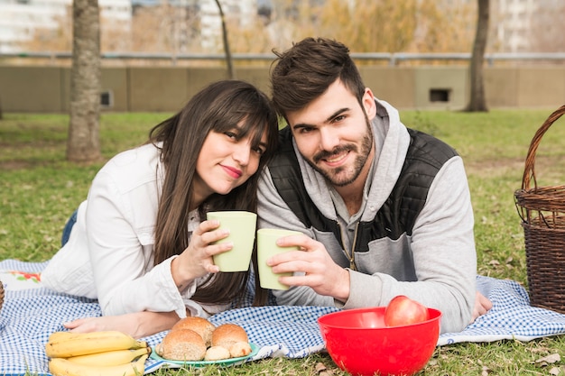 Foto grátis sorrindo, par jovem, segurando, óculos, em, piquenique, parque