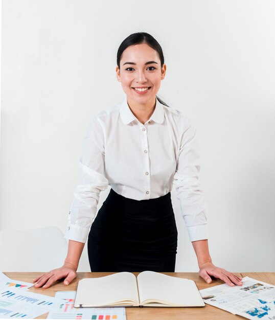 Sorrindo, retrato, de, um, jovem, mulher negócios fica, atrás de, a, escrivaninha, contra, branca, parede