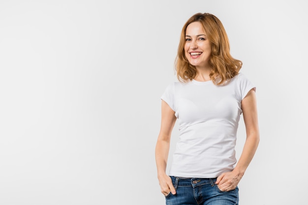 Foto grátis sorrindo, retrato, de, um, mulher jovem, com, mãos, em, dela, bolso, olhando câmera