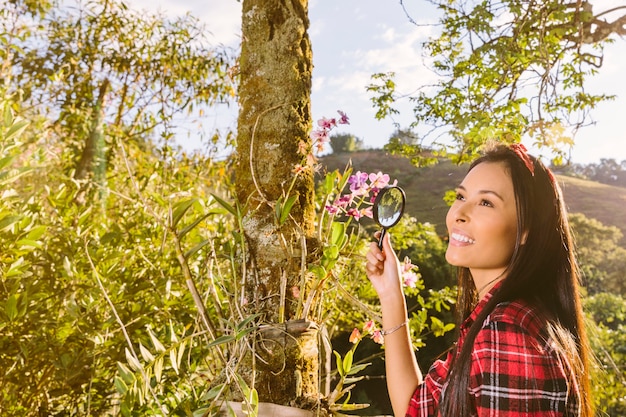 Foto grátis sorrindo, turista feminino, segurando, lupa, frente, flores