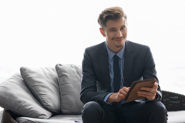 Sorriso bem sucedido Homem novo que usa o computador da tabuleta