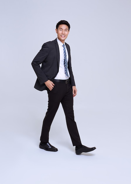 Sorriso de empresário asiático de rosto bonito e amigável no terno formal em um estúdio de fundo branco, tiro.
