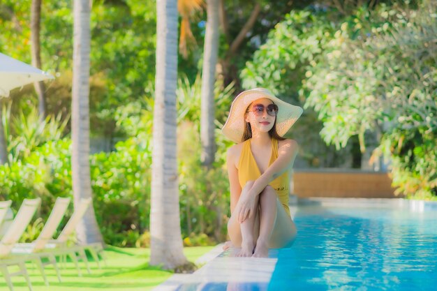 sorriso feliz da jovem mulher asiática bonita relaxe em torno da piscina no hotel resort