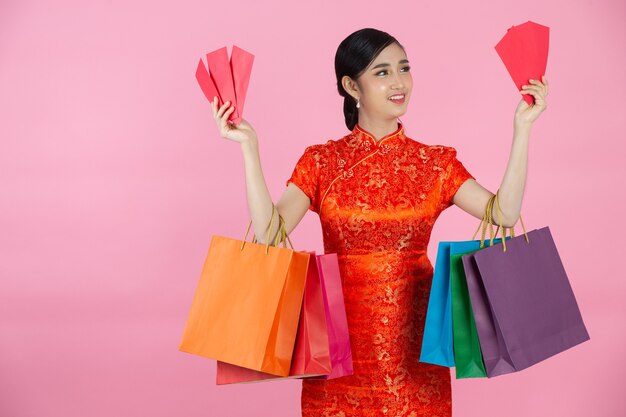 Sorriso feliz linda mulher asiática e compras no ano novo chinês no fundo rosa.