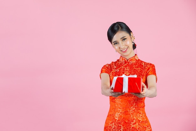 Foto grátis sorriso feliz linda mulher asiática e segurando a caixa de presente no ano novo chinês em fundo rosa.