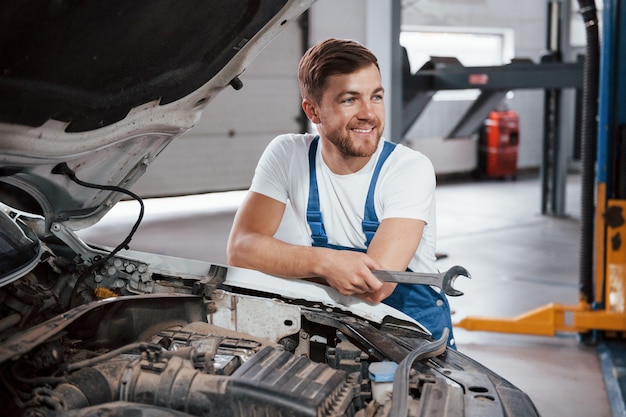 Sorriso sincero. Funcionário com uniforme azul trabalha no salão automóvel