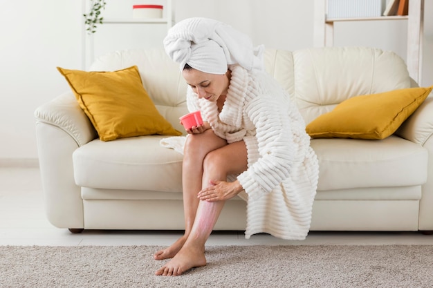 Spa em casa mulher hidrata as pernas com creme