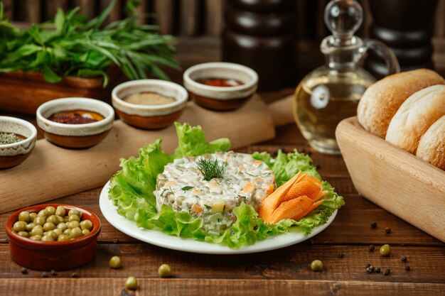 Stolichni salada russa servido em folhas de salada verde e cenoura decorativa com feijão verde