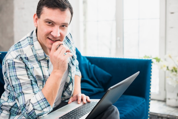 Sucesso masculino usando laptop no sofá em casa