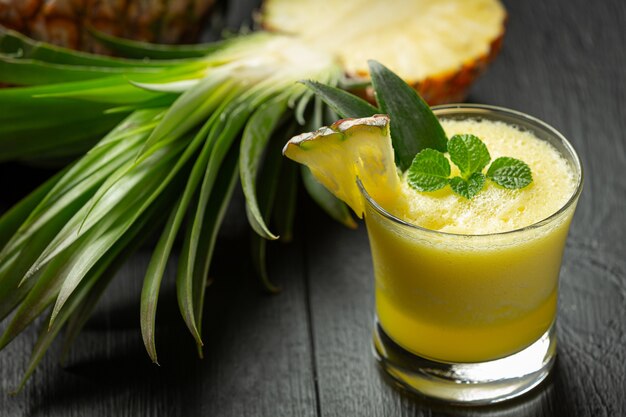 Suco de abacaxi em superfície de madeira escura