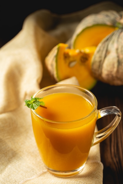 Suco de abóbora fresco em vidro na mesa de madeira.