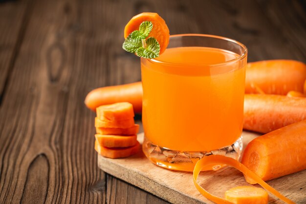 Suco de cenoura em vidro na mesa de madeira.