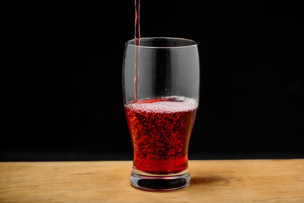 Suco de cereja derramando em vidro na mesa de madeira