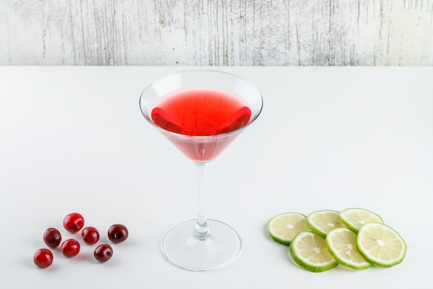 Suco de cereja em um copo com cerejas, fatias de limão vista de alto ângulo em branco