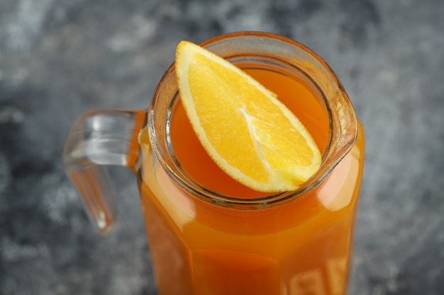 Suco de fruta puro com uma fatia de laranja na mesa de mármore.