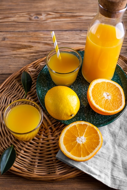 Foto grátis suco de laranja de alto ângulo em garrafa e copo