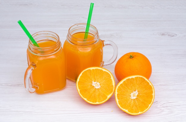 Suco de laranja em copos e frutas laranja na superfície branca